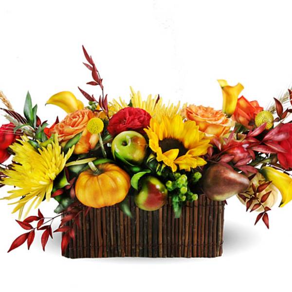 Autumn floral arrangement with sunflowers, roses, and fruit in a rectangular basket