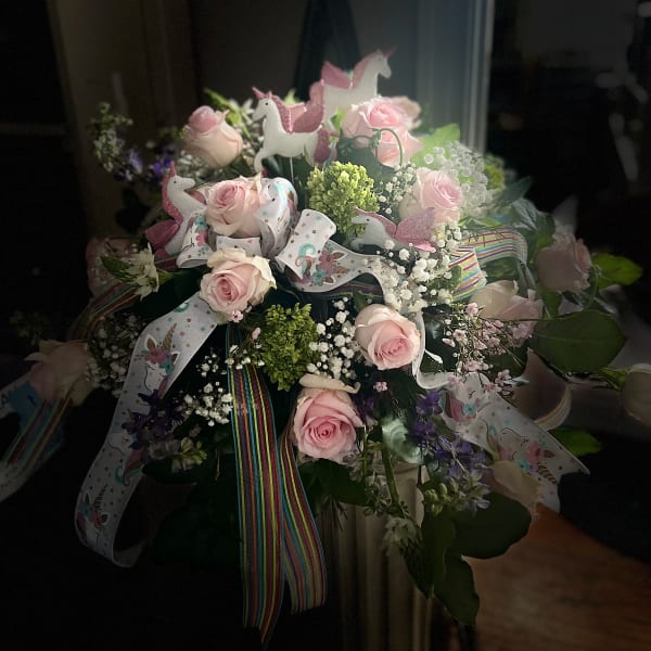 Pink roses in a bouquet with unicorn ribbons and glitter toppers