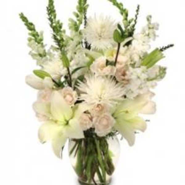 White floral arrangement in a glass vase with lilies and spiky blooms