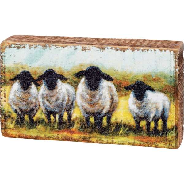 Rectangular decorative block with painted sheep on a rustic wood surface