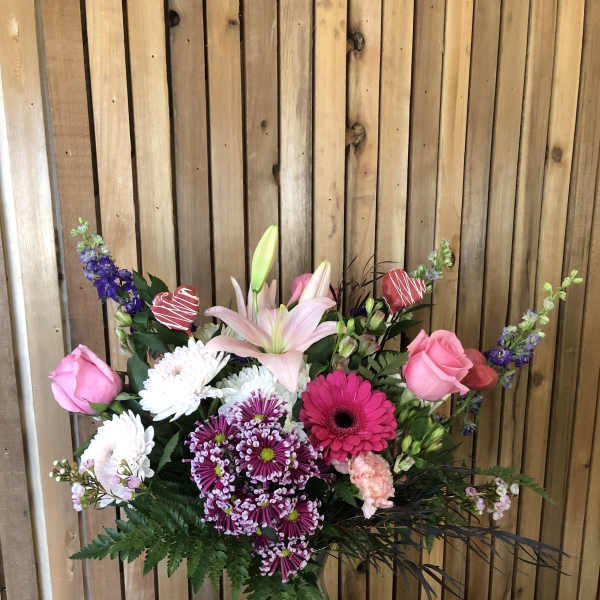Mixed bouquet in a glass vase with pink roses, lilies, and purple blooms