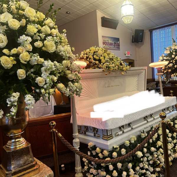 White rose funeral display around a casket with matching floral sprays