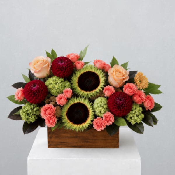Mixed bouquet with sunflowers, roses, and dahlias in a wooden box