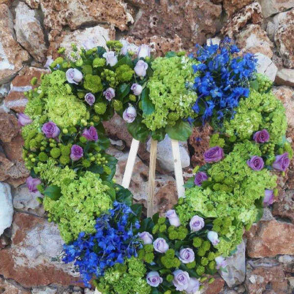 Heart-shaped floral wreath with green hydrangeas, purple roses, and blue flowers
