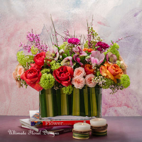 Mixed bouquet of roses and other blooms in a glass vase with candles