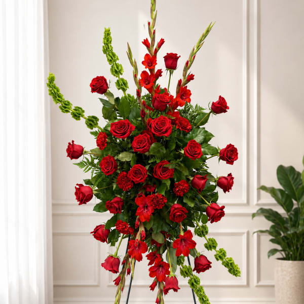 Tall standing arrangement of red roses and red flowers with green accents