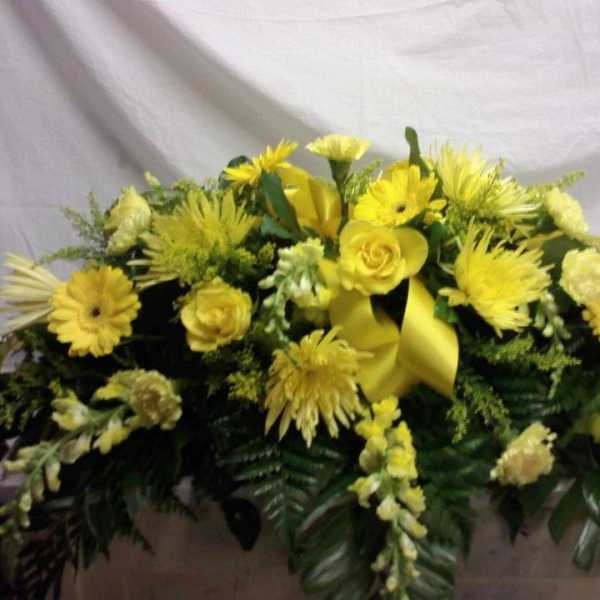 Yellow floral casket spray with roses and daisy-like blooms