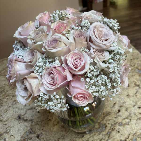 Bouquet of pale pink roses and baby's breath in a glass vase