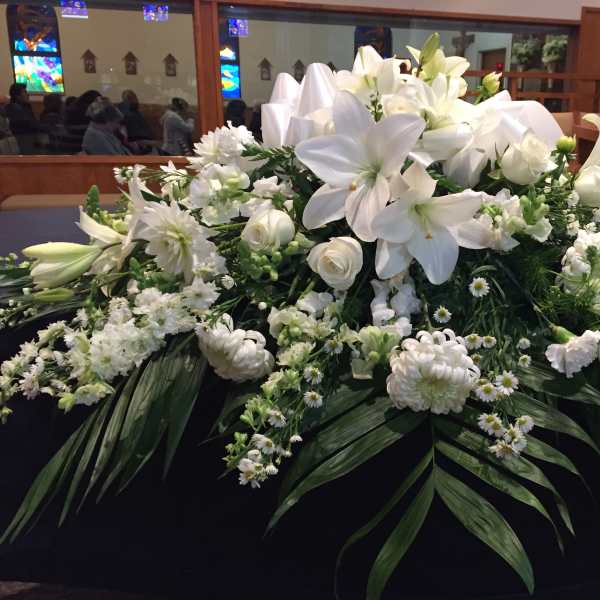 Large white floral arrangement with lilies and roses on a table