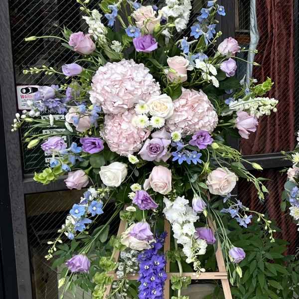Tall floral standing arrangement with pastel roses, hydrangeas, and delphinium