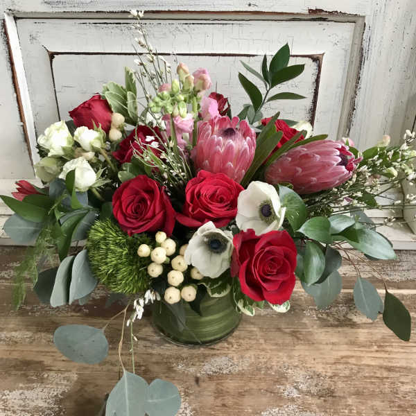 Bouquet of red roses and pink protea in a green vase