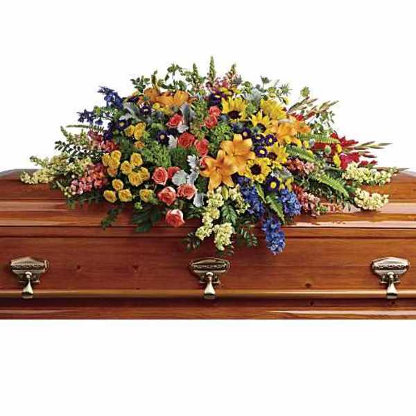 Colorful casket spray with mixed flowers on a wooden coffin