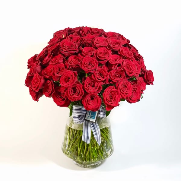 Large bouquet of red roses in a clear glass vase with a striped ribbon