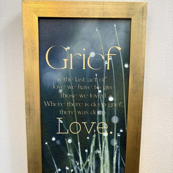 Framed grief quote print with grass and dew on a dark background