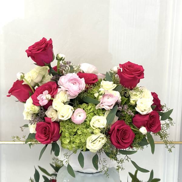 Pink and white roses with ranunculus in a white vase