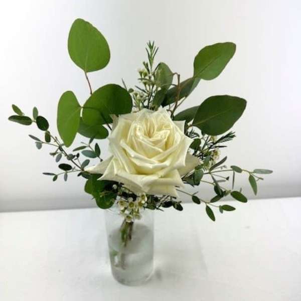 White rose in a small glass vase with greenery