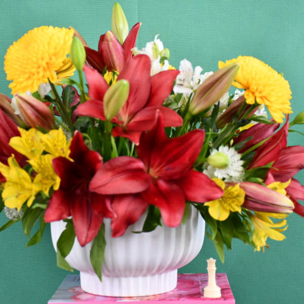 Red lilies and yellow chrysanthemums in a white vase