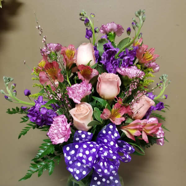 Pink and purple mixed bouquet in a glass vase with a polka-dot ribbon