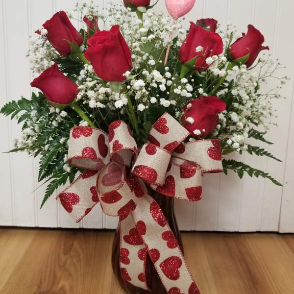 Bouquet of red roses with baby's breath in a vase and heart ribbon