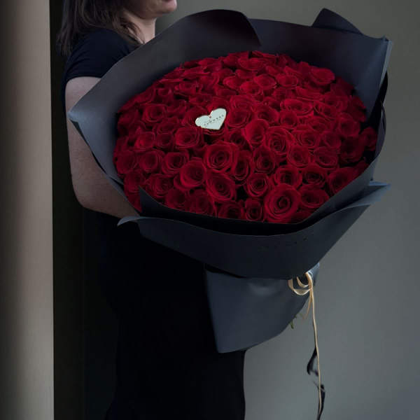 Large bouquet of red roses wrapped in dark paper