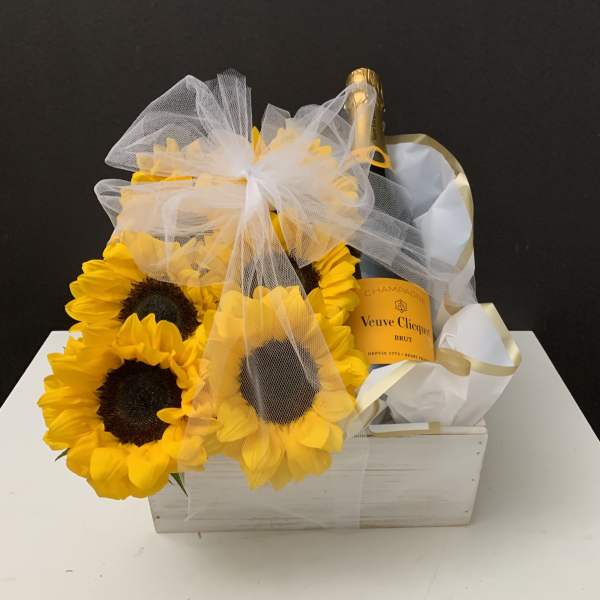 Sunflowers arranged with a champagne bottle in a white gift box