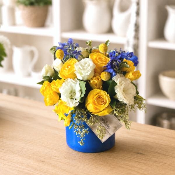 Yellow and white roses with blue flowers in a blue vase
