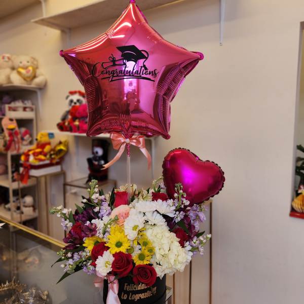 Pink graduation balloon above a mixed flower arrangement in a black box