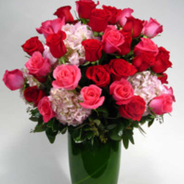 Bouquet of red and pink roses in a tall green glass vase