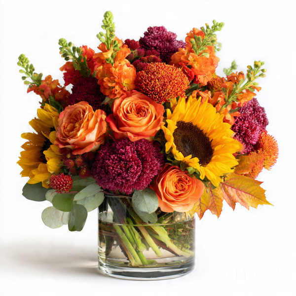 Bouquet of sunflowers, orange roses, and burgundy mums in a glass vase