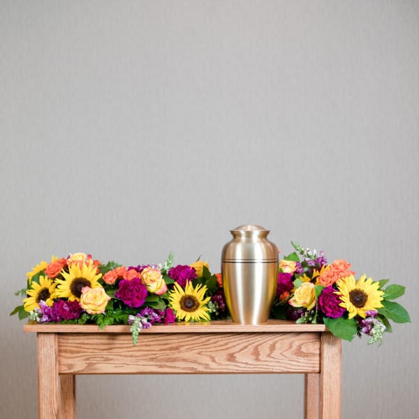 Colorful floral arrangement with a gold urn centerpiece on a wooden table