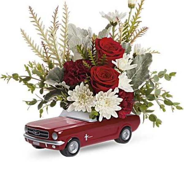 Red roses and white daisies arranged in a red toy car