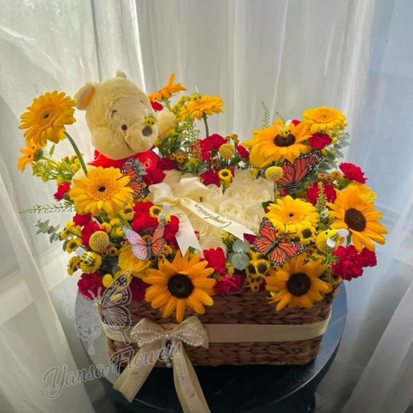 Basket arrangement of sunflowers, red flowers, and a teddy bear