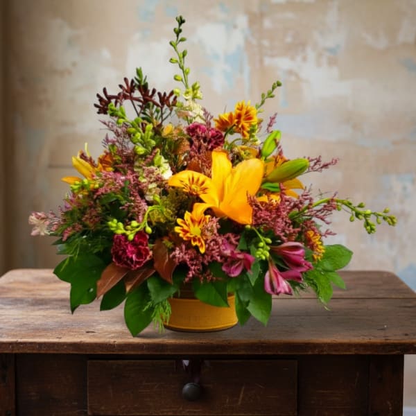 Bright mixed bouquet in a yellow container with orange lilies and pink blooms