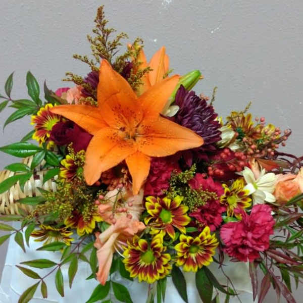 Bouquet with orange lily and mixed flowers in a woven handle wrap