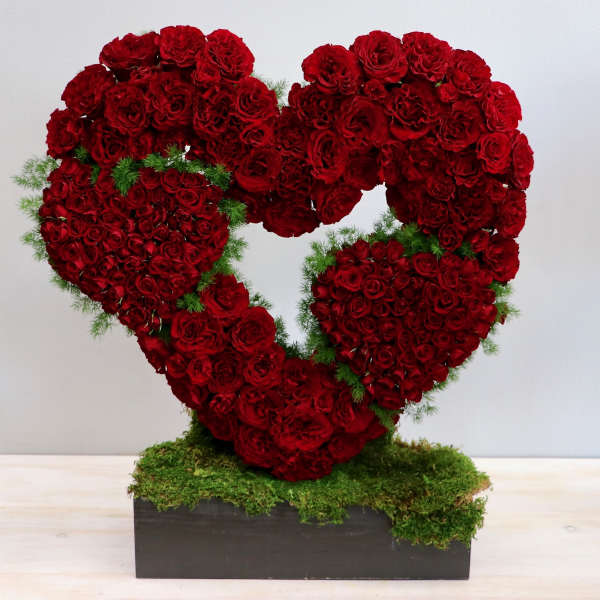 Heart-shaped arrangement of red roses on a moss-covered base
