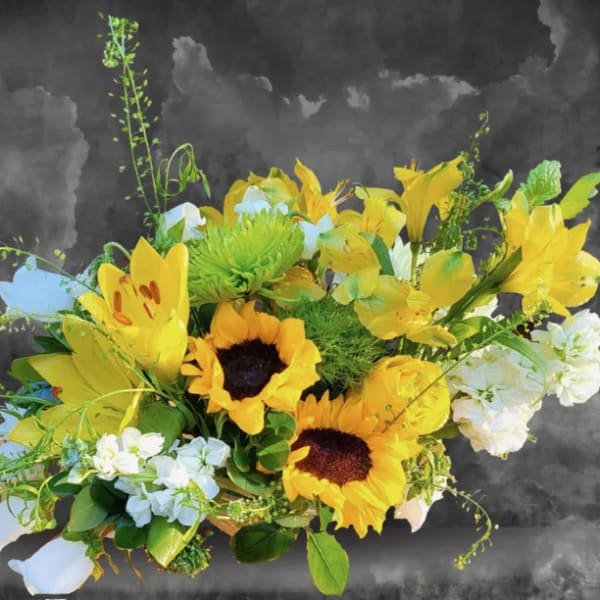 Yellow sunflowers and lilies arranged with white flowers in a low bouquet.