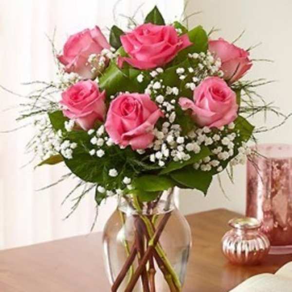 Pink roses arranged in a clear glass vase with baby's breath