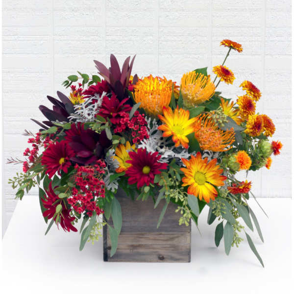 Mixed bouquet in a wooden box with orange, yellow, and burgundy flowers