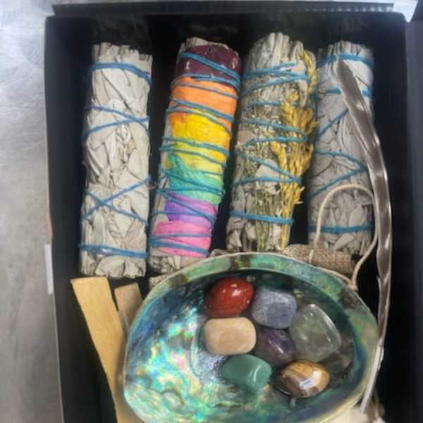 Box of bundled sage sticks, crystals, and an abalone shell