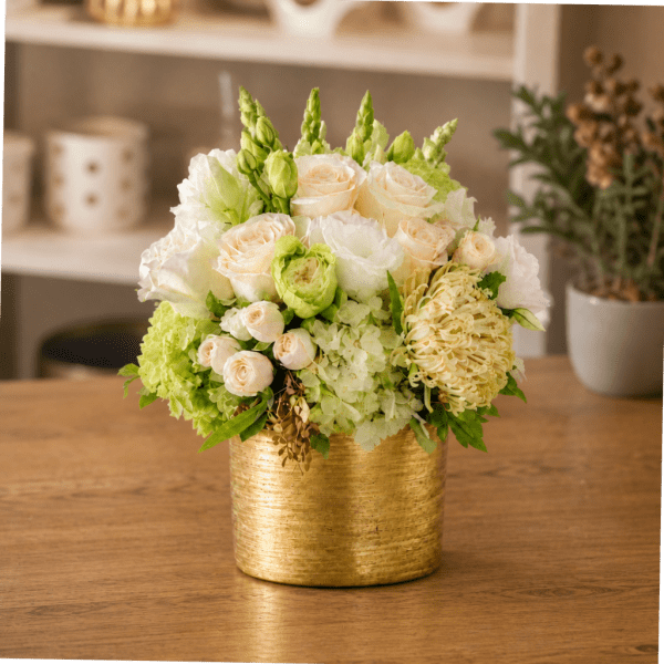 White and pale green floral arrangement in a gold container