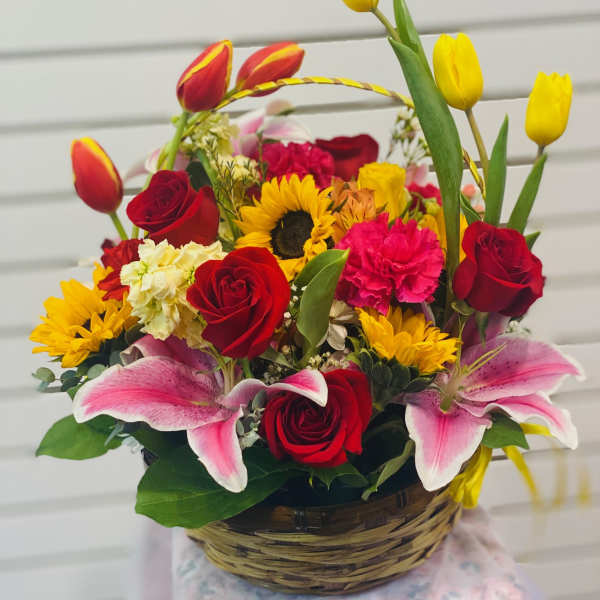 Basket arrangement of red roses, pink lilies, and yellow tulips
