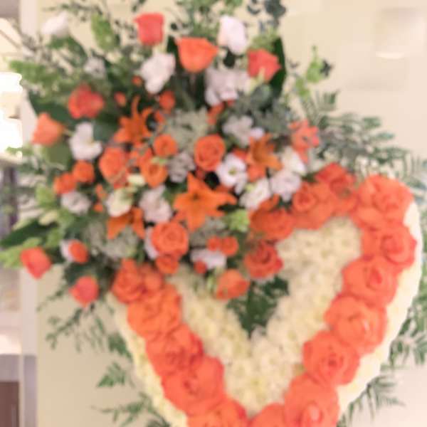 Heart-shaped floral spray with orange and white roses