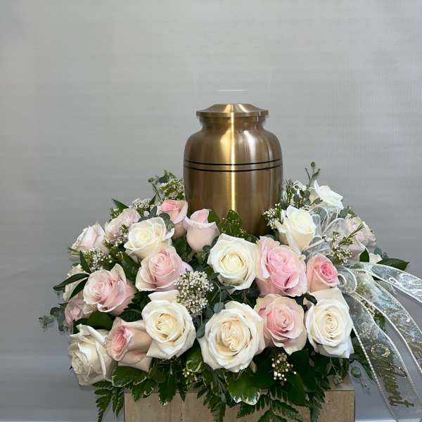 Pink and white roses arranged around a gold urn