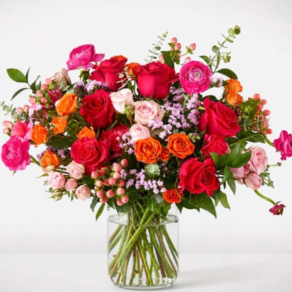 Mixed bouquet of roses and ranunculus in a clear glass vase