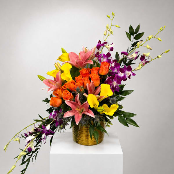 Colorful bouquet of roses, lilies, and orchids in a gold vase