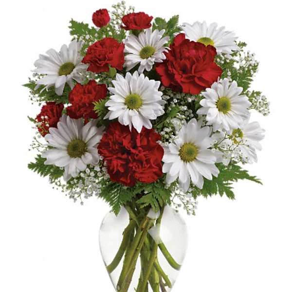 Bouquet of red carnations and white daisies in a clear glass vase