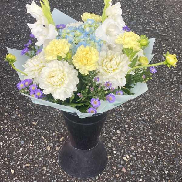 White and yellow bouquet with purple accents in a black vase