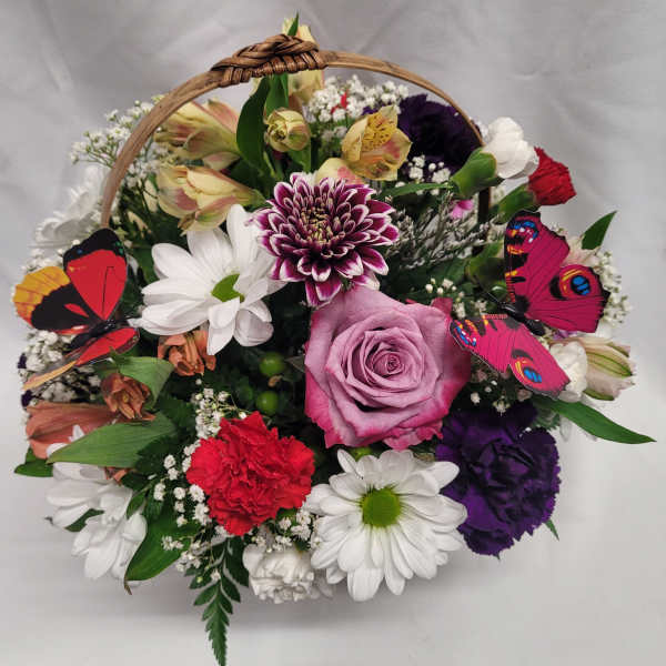 Basket arrangement with mixed flowers and colorful butterfly decorations