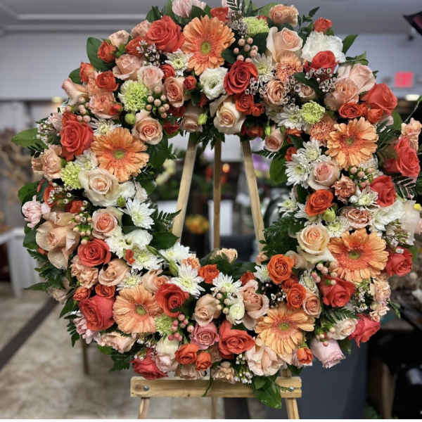 Large floral wreath with roses, gerbera daisies, and small filler flowers