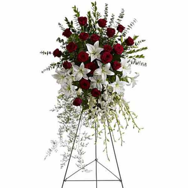 Standing floral spray with red roses and white lilies on an easel